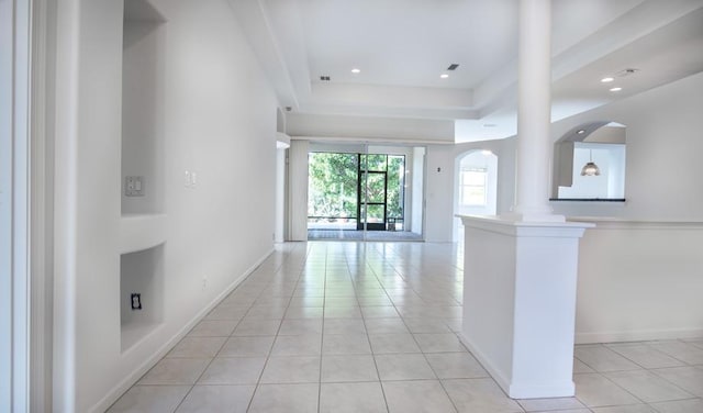 unfurnished living room with light tile patterned floors, decorative columns, and a raised ceiling