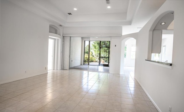 spare room featuring light tile patterned floors and a raised ceiling