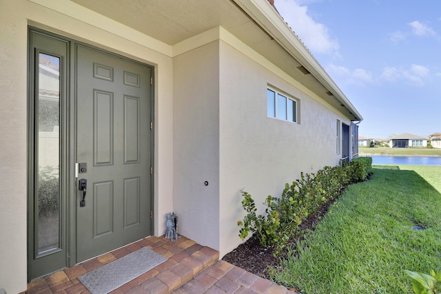 view of exterior entry with a lawn and a water view