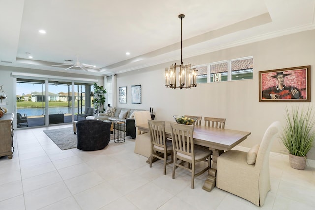 tiled dining room featuring a raised ceiling, crown molding, a water view, and ceiling fan with notable chandelier