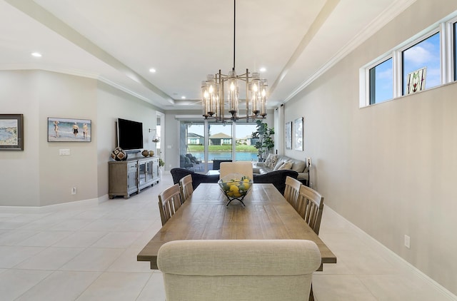 dining area with a notable chandelier, light tile patterned floors, ornamental molding, and a tray ceiling