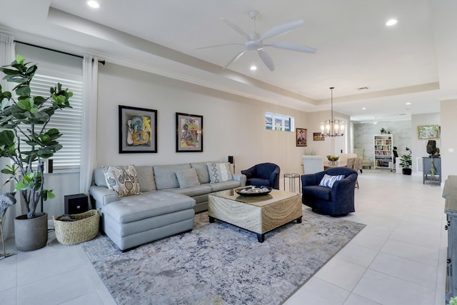 living room with ceiling fan with notable chandelier, a healthy amount of sunlight, light tile patterned floors, and a tray ceiling