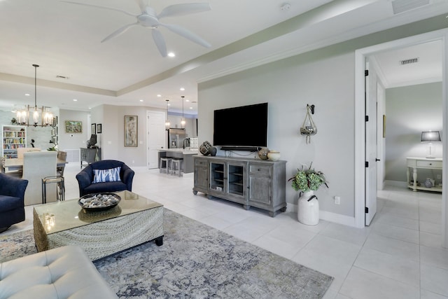 tiled living room with ceiling fan with notable chandelier and a raised ceiling