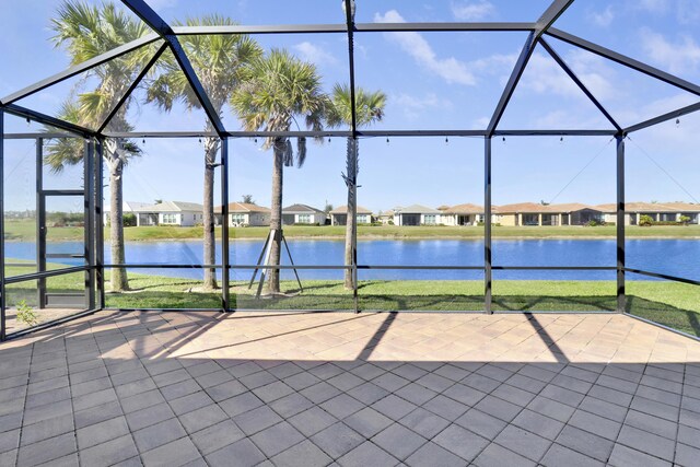 view of patio / terrace featuring a lanai, ceiling fan, and a water view