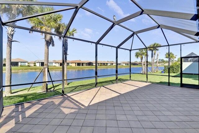 view of patio with glass enclosure and a water view