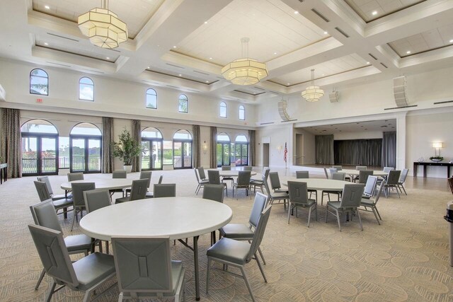 dining space with beam ceiling, light carpet, a high ceiling, and coffered ceiling