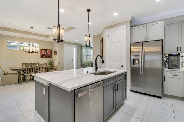 kitchen with dishwasher, sink, light stone counters, gray cabinets, and a center island with sink