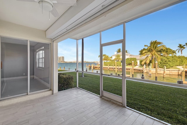 unfurnished sunroom featuring ceiling fan and a water view