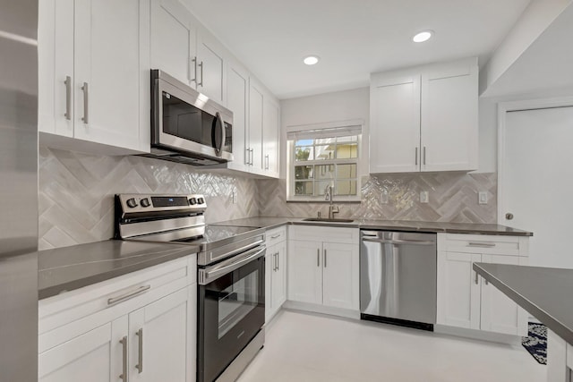 kitchen featuring white cabinets, appliances with stainless steel finishes, decorative backsplash, and sink