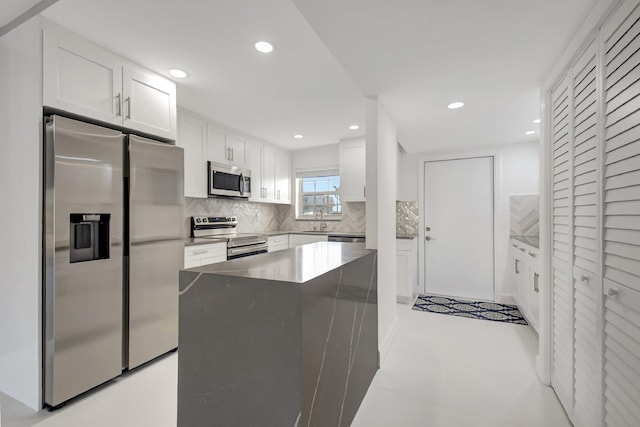 kitchen with white cabinetry, sink, a center island, tasteful backsplash, and appliances with stainless steel finishes