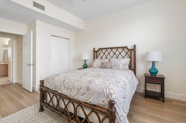 bedroom with ensuite bath, light hardwood / wood-style flooring, and a closet