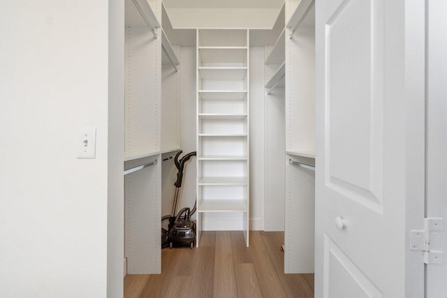 walk in closet with light hardwood / wood-style flooring