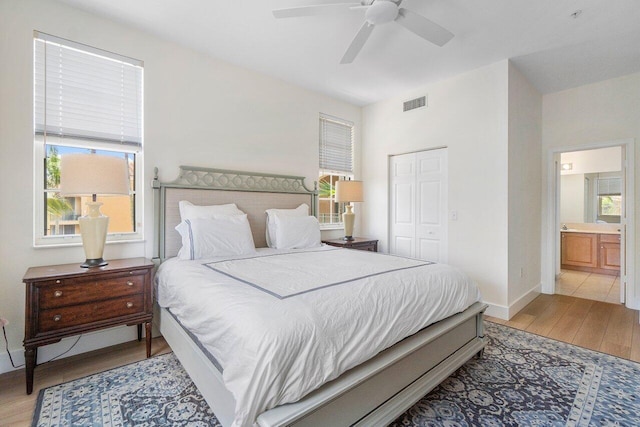 bedroom with light wood-type flooring, a closet, ensuite bath, and ceiling fan