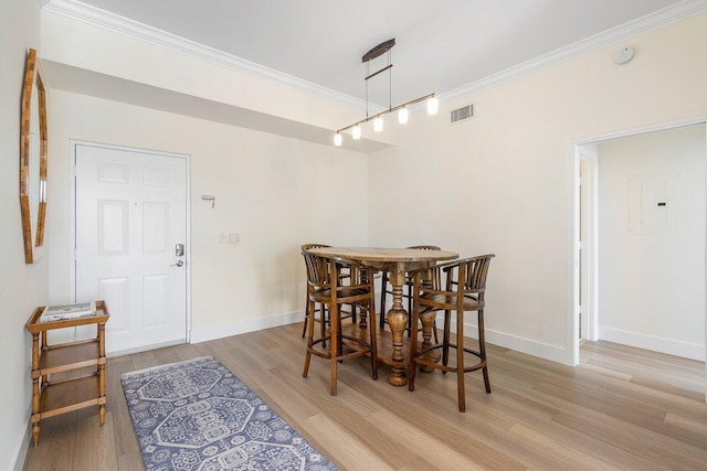 dining space with light wood-type flooring, ornamental molding, and electric panel