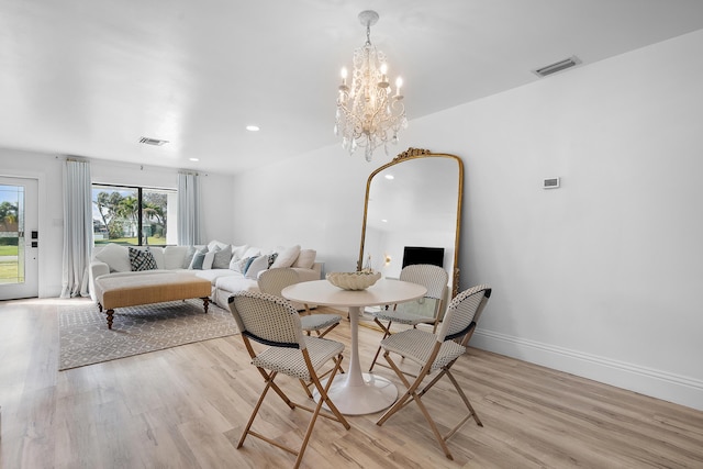 dining area with light hardwood / wood-style flooring and a notable chandelier