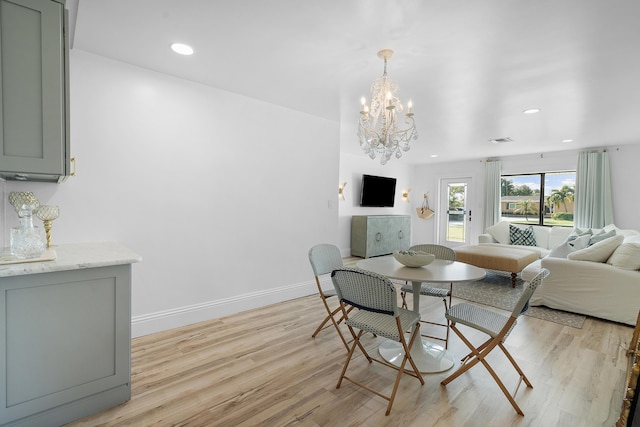 dining room with light hardwood / wood-style floors and an inviting chandelier