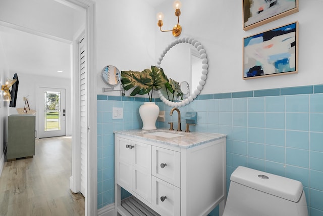 bathroom with tile walls, vanity, toilet, and hardwood / wood-style floors