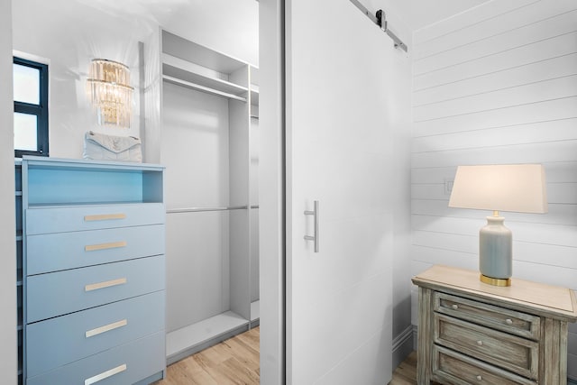 walk in closet featuring a barn door and light hardwood / wood-style floors