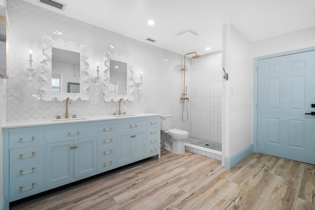 bathroom featuring toilet, hardwood / wood-style flooring, vanity, and tiled shower