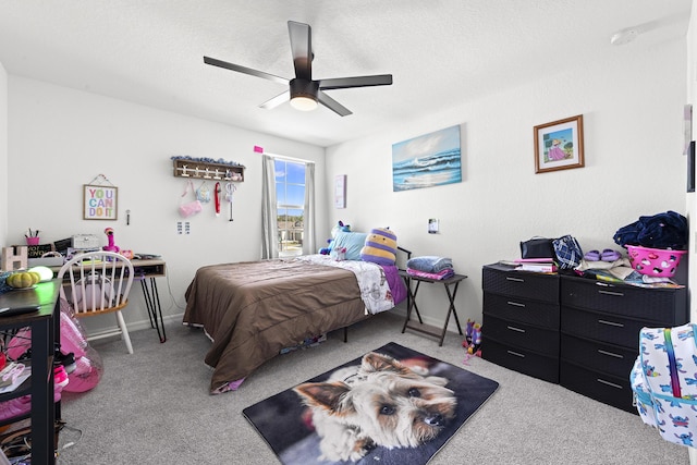 carpeted bedroom featuring ceiling fan and a textured ceiling