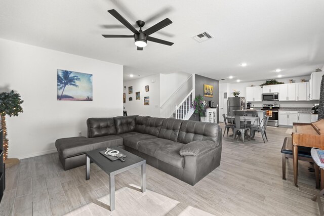 living room with ceiling fan, light hardwood / wood-style floors, and a textured ceiling