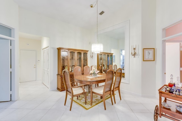 tiled dining space featuring a towering ceiling and a chandelier