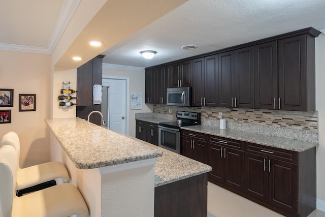 kitchen with kitchen peninsula, stainless steel appliances, backsplash, ornamental molding, and a kitchen breakfast bar