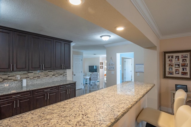 kitchen with ornamental molding, backsplash, and light stone countertops