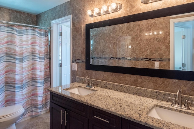 bathroom with tile walls, curtained shower, vanity, and toilet