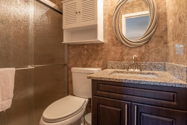 bathroom with tile walls, vanity, and toilet