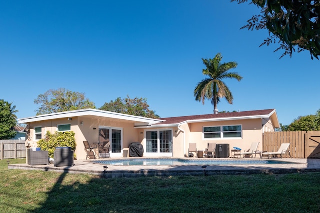 rear view of house with a patio area, central air condition unit, a yard, and a fenced in pool