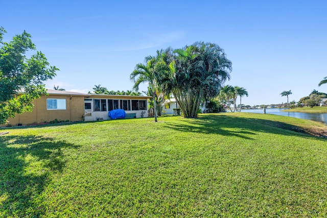 view of yard with a sunroom and a water view