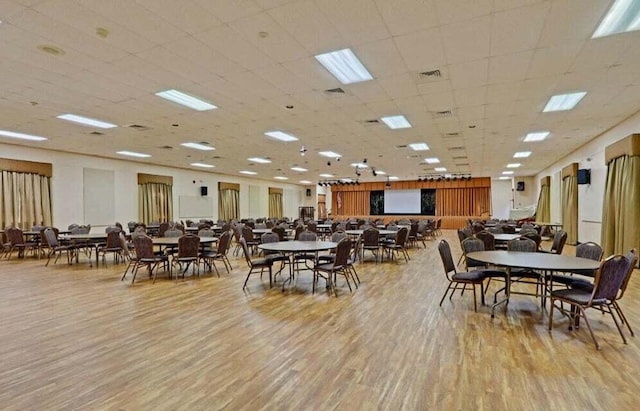 dining area with a paneled ceiling and light wood-type flooring