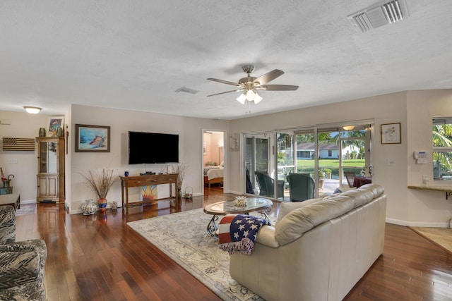 living room featuring a textured ceiling, dark hardwood / wood-style floors, and ceiling fan