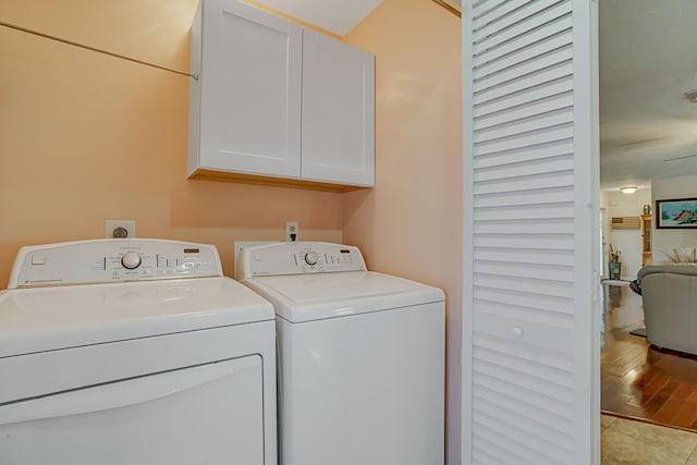 clothes washing area featuring cabinets, light tile patterned floors, and washing machine and clothes dryer