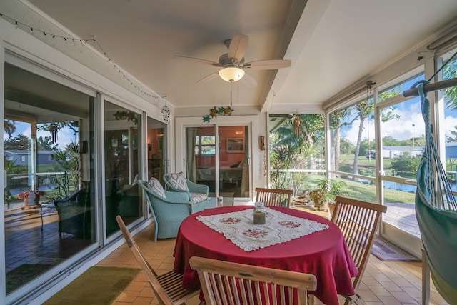 sunroom / solarium with beamed ceiling, ceiling fan, and a water view