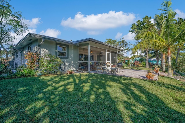 back of house featuring a lawn, a sunroom, and a patio area