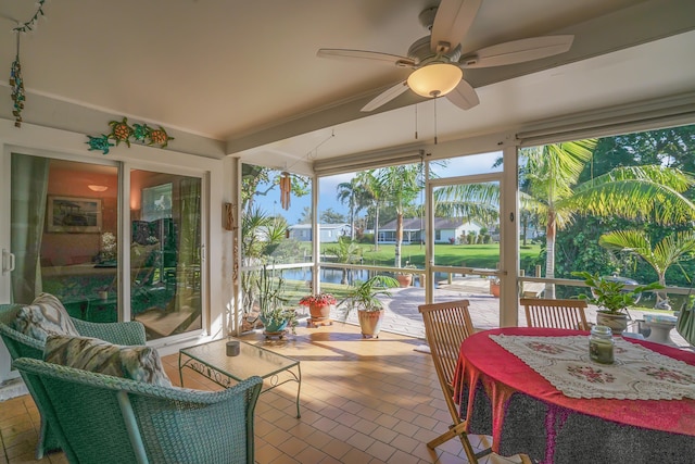 sunroom / solarium with ceiling fan and a water view