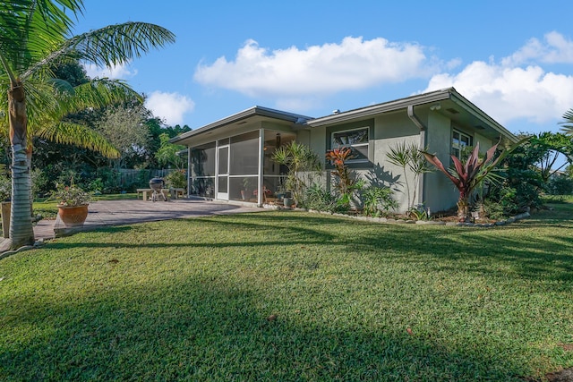 back of property featuring a lawn, a patio area, and a sunroom