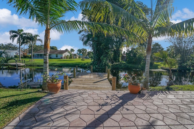 view of home's community featuring a yard, a water view, and a dock