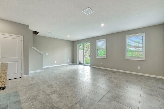 tiled empty room featuring a textured ceiling