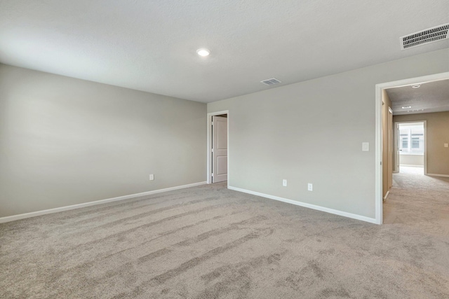 spare room with light carpet and a textured ceiling