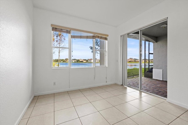 spare room featuring a water view, light tile patterned floors, and a wealth of natural light