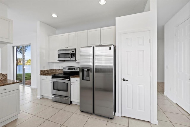 kitchen featuring dark stone countertops, white cabinetry, light tile patterned floors, and stainless steel appliances