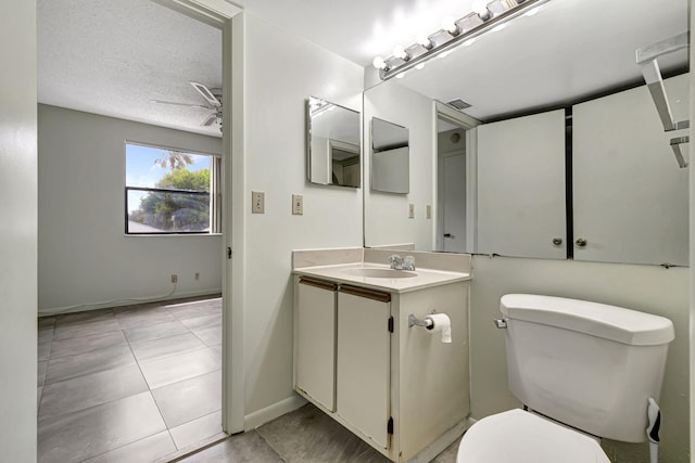 bathroom with ceiling fan, tile patterned flooring, a textured ceiling, toilet, and vanity