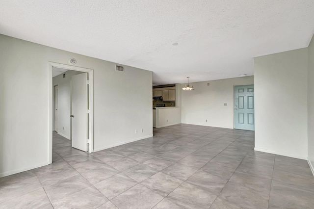 empty room with a textured ceiling and a notable chandelier