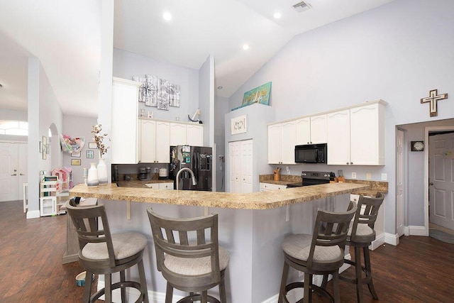 kitchen with black appliances, a kitchen breakfast bar, dark hardwood / wood-style flooring, and kitchen peninsula