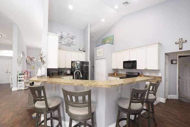 kitchen featuring black appliances, white cabinetry, a kitchen bar, and kitchen peninsula