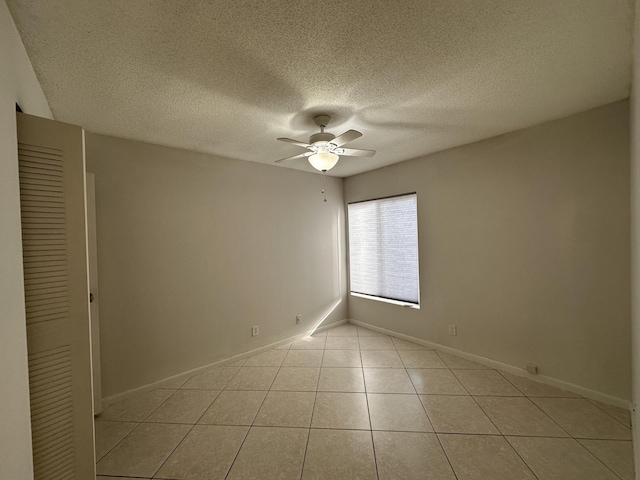 tiled empty room with ceiling fan and a textured ceiling