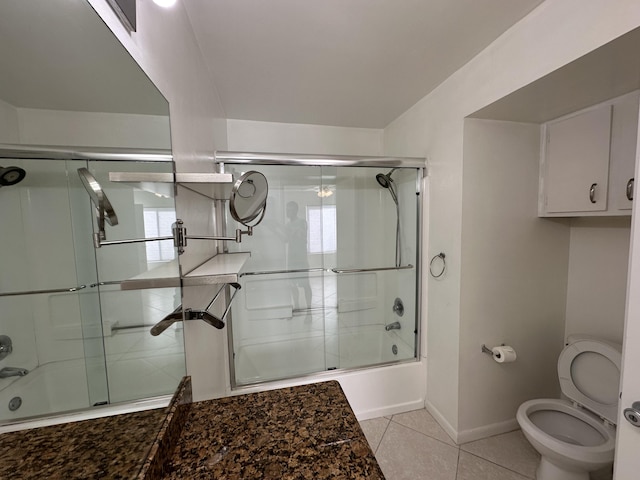 bathroom with toilet, tile patterned floors, shower / bath combination with glass door, and a wealth of natural light